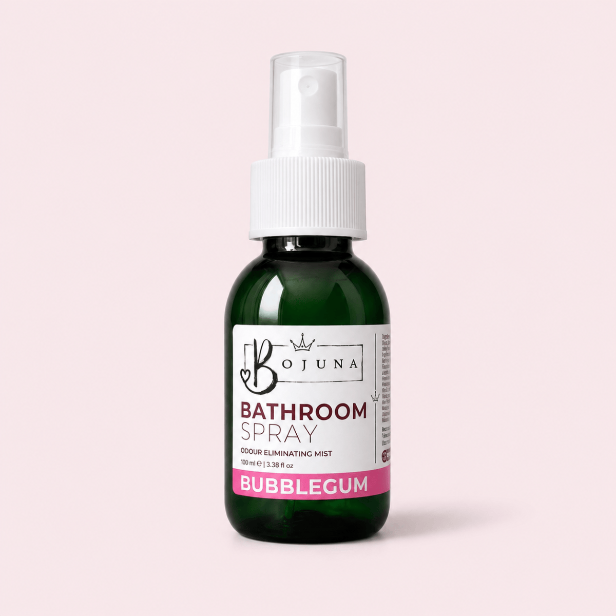 A dark green glass spray bottle of Bojuna Bathroom Spray with a white pump dispenser and a white label featuring pink and black text, set against a solid pale pink background.