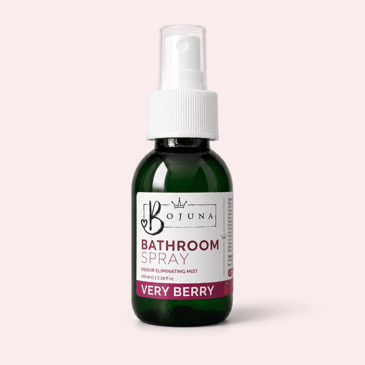 A dark green glass spray bottle of Bojuna Bathroom Spray, Very Berry, with a white pump and a white label, set against a solid pale pink background.
