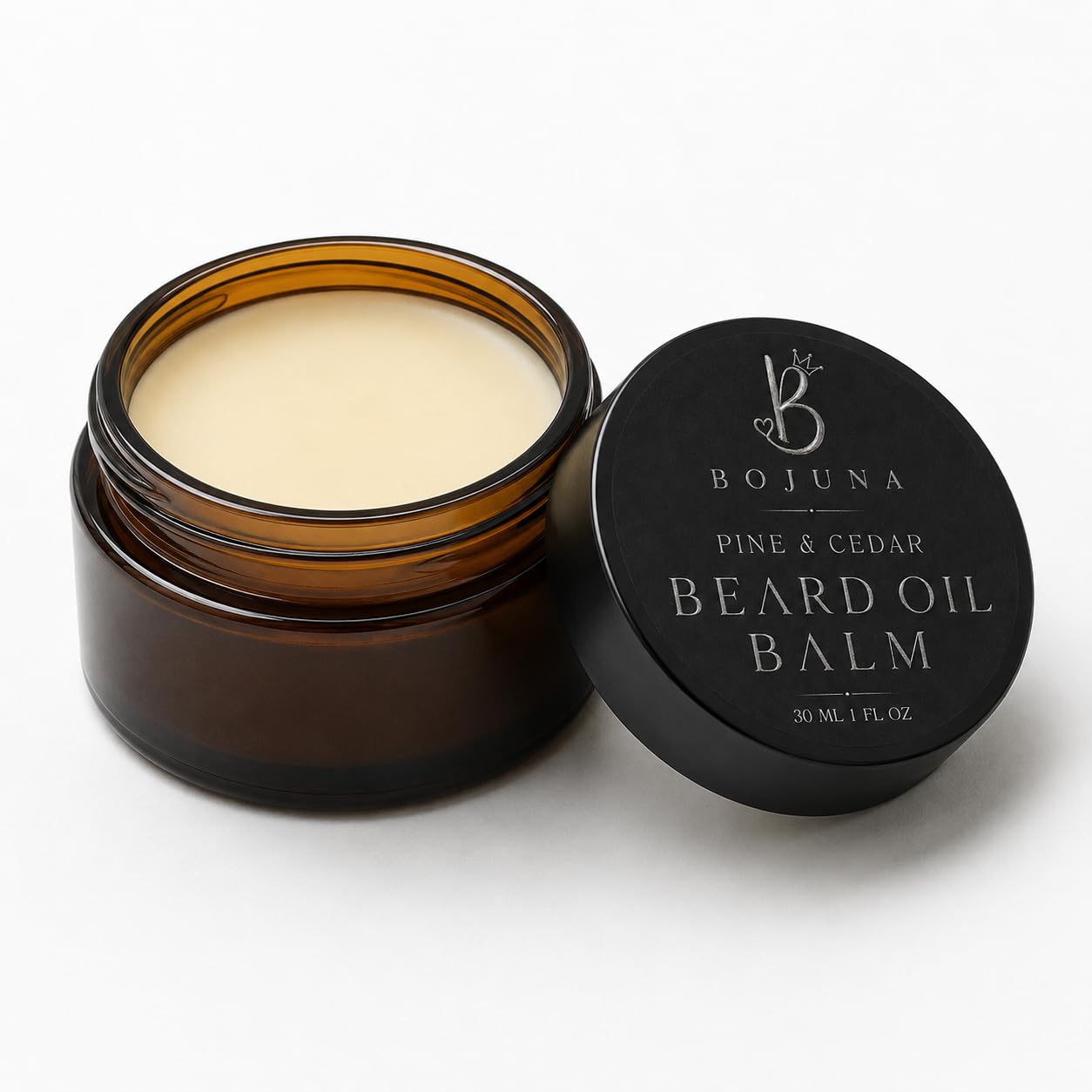 An open amber glass jar of Bojuna Pine & Cedar Beard Oil Balm next to its black lid on a clean white background.
