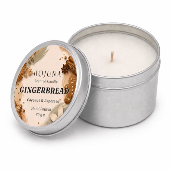 An open silver metal tin candle next to its lid, which features a round label reading 'BOJUNA Scented Candle GINGERBREAD Coconut & Rapeseed Hand Poured 80 g e'. The candle wax inside is a warm off-white/cream color.