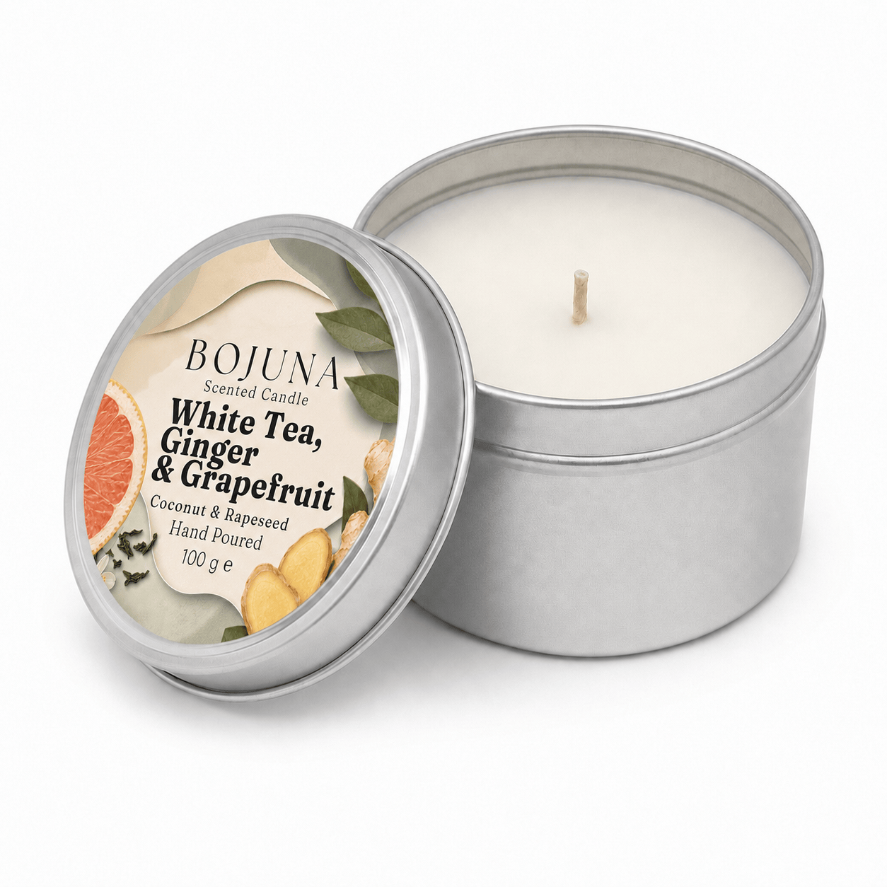 An open silver metal tin candle next to its lid, which features a printed label for 'Bojuna' White Tea, Ginger & Grapefruit scented candle. The candle wax is off-white and a single wick is visible in the center of the tin, set against a clean white background.