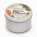 A round silver metal tin candle with a white lid label reading BOJUNA White Tea, Ginger & Grapefruit, on a clean white background.