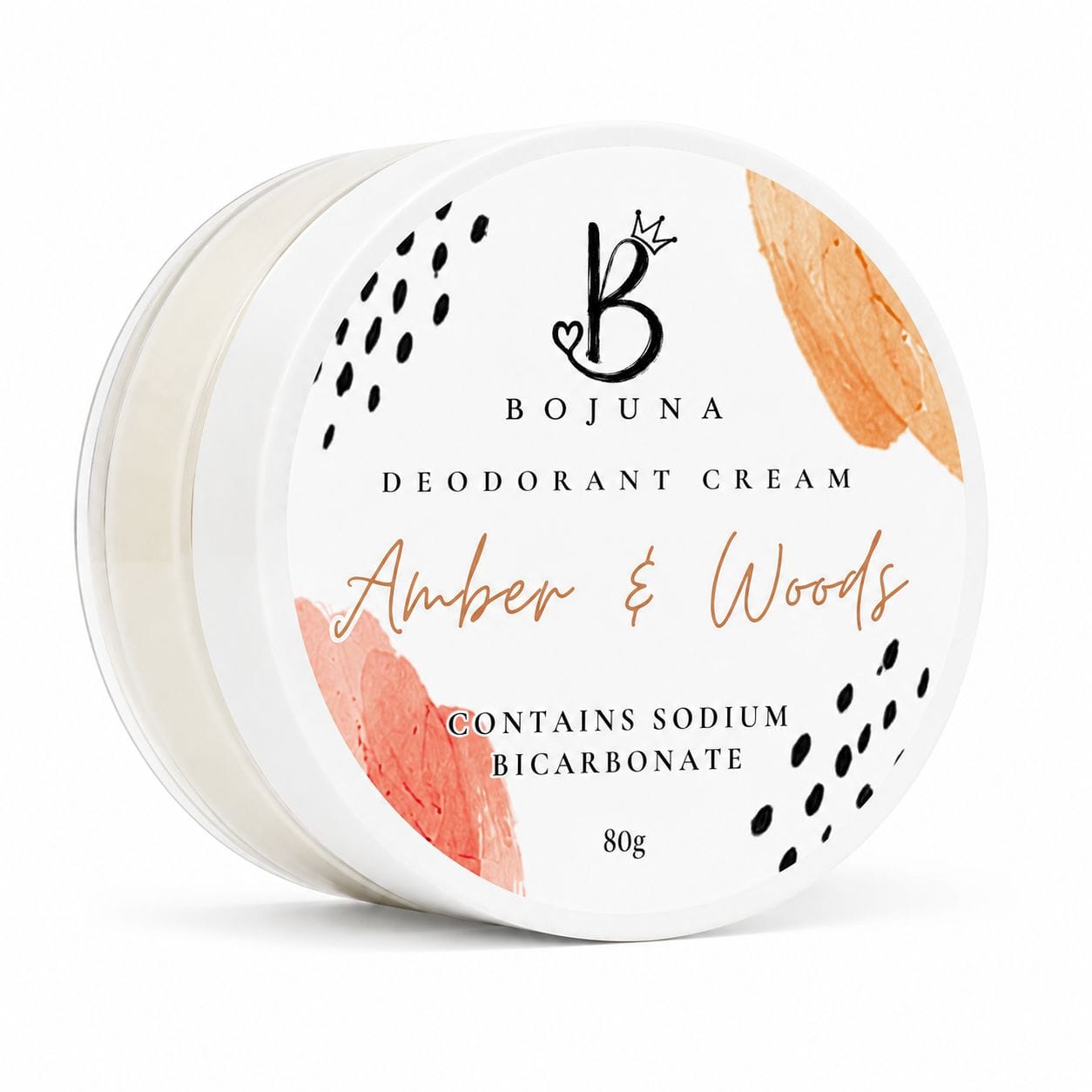 A round white jar of Bojuna Deodorant Cream in the 'Amber & Woods' scent, featuring a white lid decorated with black polka dots, coral watercolor accents, and gold foil lettering.