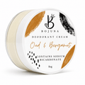 A round white plastic tub of Bojuna Oud & Bergamot Deodorant Cream, showing the cream inside and a decorative label with gold and black brushstrokes.