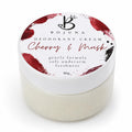 A jar of Bojuna Deodorant Cream in the Cherry & Musk scent, featuring a white lid with red and black paint splatter designs and a white jar of cream underneath, shot against a white background.