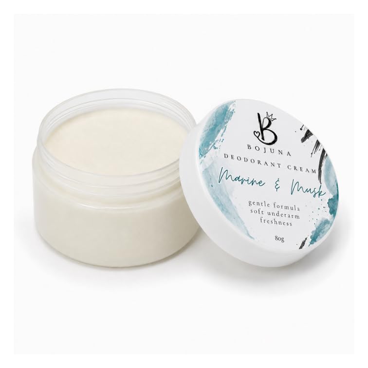 An open clear plastic jar of Bojuna Deodorant Cream showing the off-white cream inside, with its matching lid leaning beside it on a clean white background.