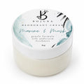 A round white plastic jar of Bojuna Marine & Musk Deodorant Cream, showing the creamy off-white product inside and a white lid decorated with a watercolor design in teal, black, and gold.