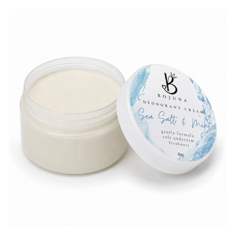An open clear plastic jar of Bojuna Deodorant Cream with sea salt and mint scent, next to its white lid featuring blue water graphics, on a white background.