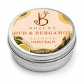 A round silver metal tin of Bojuna Oud & Bergamot Scented Hand Balm, featuring a light peach label with botanical illustrations of bergamot and a crown logo.