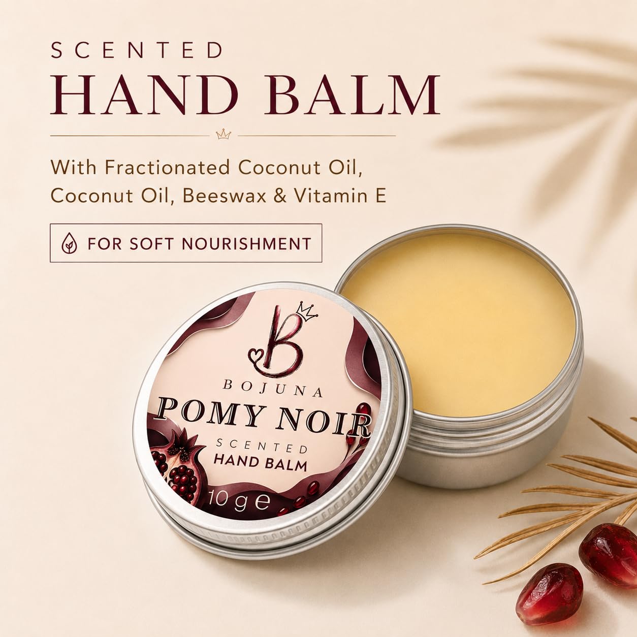 An open silver tin of Bojuna Pomy Noir Scented Hand Balm next to its decorated lid, set against a warm beige background with text detailing its ingredients and a small decorative botanical element.