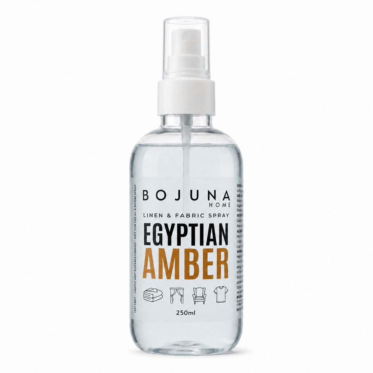 A clear plastic spray bottle of Bojuna Home Egyptian Amber Linen & Fabric Spray, featuring a white spray nozzle and a label with black and orange text, set against a plain white background.