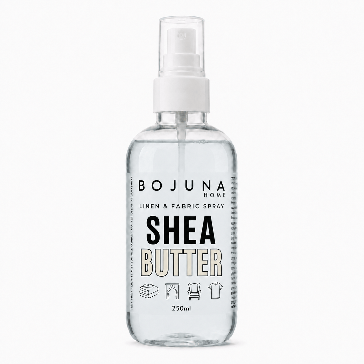 A clear plastic spray bottle of Bojuna Home Shea Butter Linen & Fabric Spray, containing a transparent liquid, with a white spray nozzle and a white label featuring black and beige text.