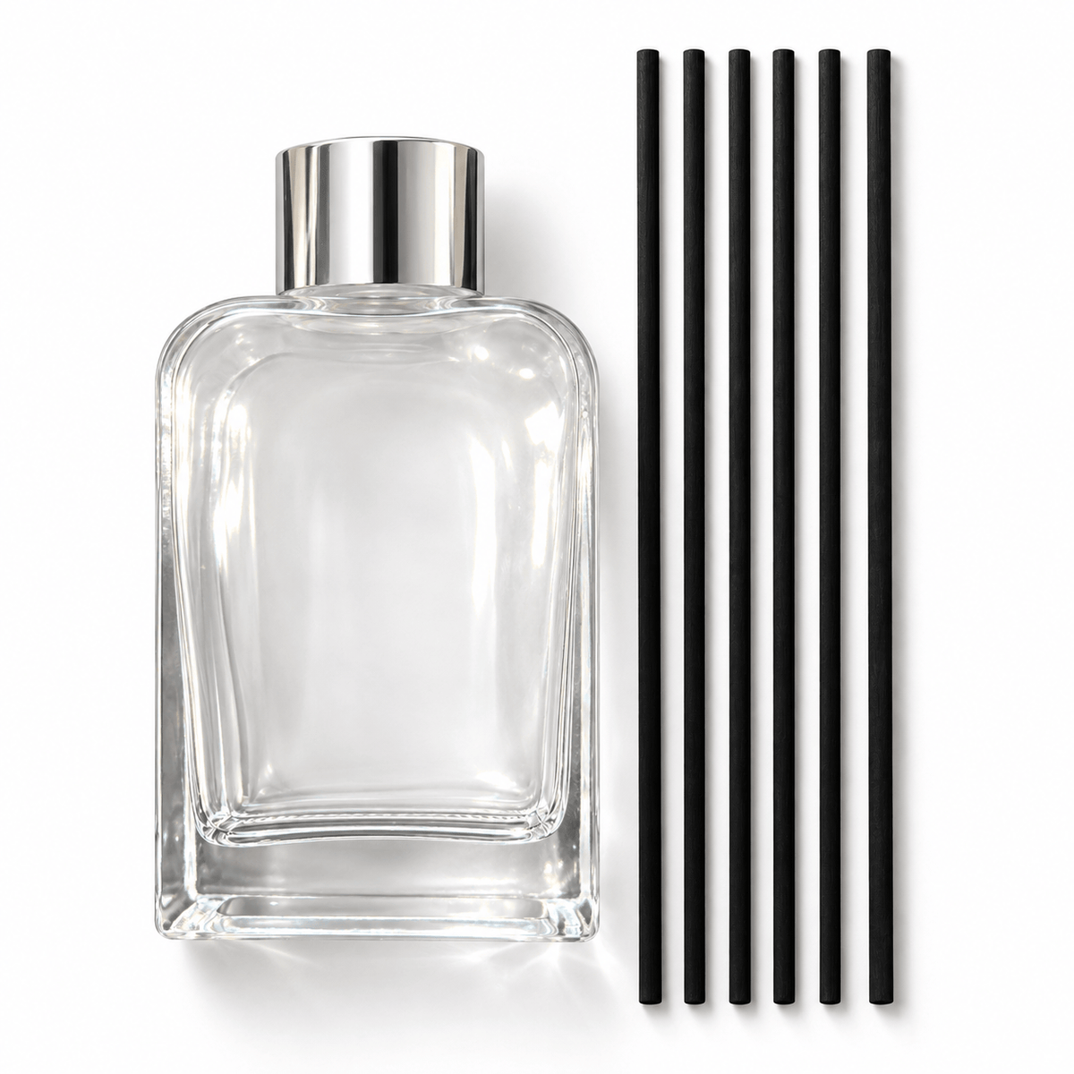 Clear glass reed diffuser bottle with a silver collar and six separate black reeds beside it, available from Bojuna.