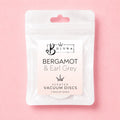 A white resealable pouch of Bojuna Scented Vacuum Discs in the Bergamot & Earl Grey scent, shown on a solid pink background.