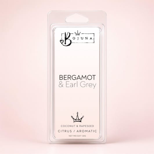 A packaged fragrance wax melt in a clear plastic clamshell package labeled 'Bojuna Bergamot & Earl Grey' on a soft pink background.