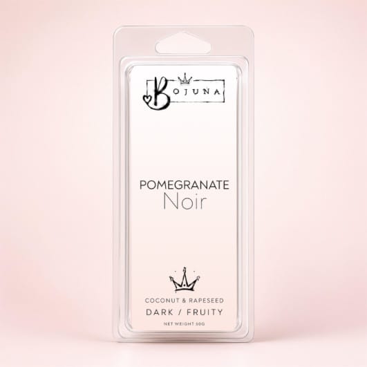 A packaged wax melt in a clear plastic clamshell package with a white insert card. The card reads 'BOJUNA' at the top and 'POMEGRANATE Noir' in the center, with additional text 'COCONUT & RAPESSEED DARK / FRUITY' and 'NET WEIGHT 50g' at the bottom.