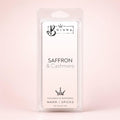 A packaged Bojuna Saffron & Cashmere wax melt in a clear plastic clamshell package, set against a soft, pale pink background.