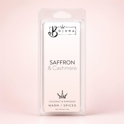 A packaged Bojuna Saffron & Cashmere wax melt in a clear plastic clamshell package, set against a soft, pale pink background.
